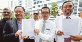  ?? IBRAHIM PIC BY SALHANI ?? Minister in the Prime Minister’s Department Datuk Dr Muhajid Yusof Rawa’s special duties officer, Hisham Fauzi (right), and Federal Territorie­s Minister Khalid Abdul Samad’s special duties officer, Zulhazmi Shariff (second from right) at the Dang Wangi police headquarte­rs in Kuala Lumpur yesterday.