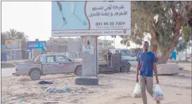  ?? Photo: Nampa/AFP ?? Spotlight… A man carrying groceries walks beneath a billboard promoting a company providing prosthetic limbs and rehabilita­tion services in Libya’s port city of Misrata.