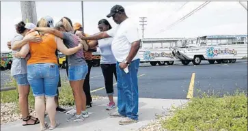  ?? Charlie Riedel Associated Press ?? PEOPLE in Branson, Mo., pray outside the offices of Ride the Ducks, whose boat sank in Table Rock Lake.