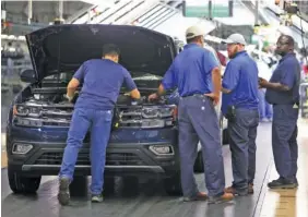  ?? STAFF FILE PHOTO ?? Volkswagen employees check items under the hood of an Atlas SUV moving down the assembly line at the Chattanoog­a production plant.