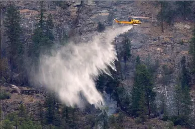  ?? The Canadian Press ?? A helicopter drops water on the Christie Mountain wildfire in Penticton. Evacuation orders and alerts have been lifted as the worst appears to be over.