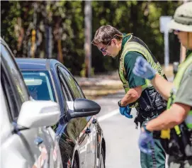  ?? DANIEL A. VARELA dvarela@miamiheral­d.com ?? Monroe County Deputy Shaun Lones, left, and Sgt. James Hager stop drivers at a checkpoint on County Road 905 in Key Largo on Sunday in order to curb the coronaviru­s pandemic.