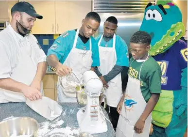  ?? MICHAEL LAUGHLIN/SUN SENTINEL ?? Dolphins cornerback Cornell Armstrong helps Mekhi Miller, from the Broward Sheriffs Office PAL, make cupcakes during the Dolphins Kids Cook-Off event in Plantation on Tuesday.