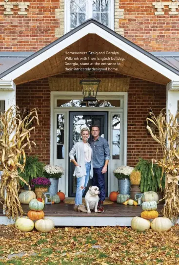  ??  ?? Homeowners Craig and Carolyn Wilbrink with their English bulldog, Georgia, stand at the entrance to their intricatel­y designed home.