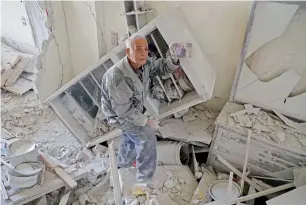  ?? AFP ?? An elderly Syrian man shows a family picture after he recovered it from the rubble of his house in Kafar Batna in Eastern Ghouta following air strikes by Syrian government forces. —