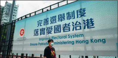  ?? ASSOCIATED PRESS ?? A man walks past a government advertisem­ent to promote the new Hong Kong electoral system reform, in Hong Kong, March 30.