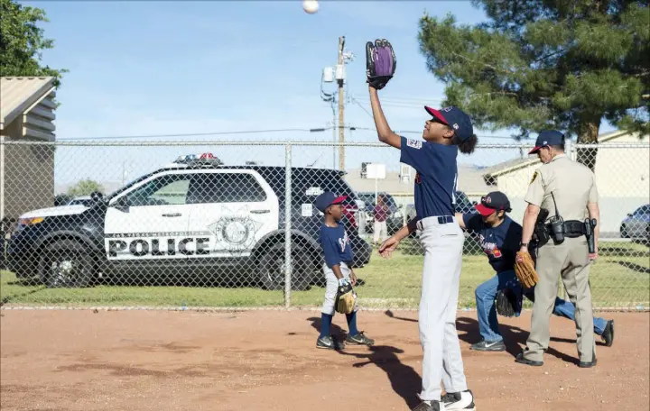  ?? Bridget Bennett Las Vegas Review-Journal @bridgetkbe­nnett ?? Alayja Grayson, 11, warms up with teammates as Metro officer Dave Shive coaches them before a Bolden Little League game Thursday at Doolittle Field. Bolden Little League, co-founded by Mario Berlanga Jr., owner of Mario’s Westside Market, and Bolden...
