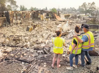  ?? Santiago Mejia / The Chronicle ?? Anna Noland (left), 16-year-old Kailyn Nash and James Nash at their burned home in the Lake Keswick Estates neighborho­od of Redding. Thousands of firefighte­rs scrambled to push the fire away from the shaken Shasta County town.