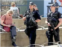  ??  ?? Armed police officers carry their weapons as they pass an "I Love MCR" symbol in Manchester, northwest England on May 26. AFP PHOTO / Lindsey Parnaby