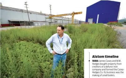  ?? STAFF PHOTO BY TIM BARBER ?? Jimmy White, president of Urban Story Ventures LLC, stands in overgrown weeds at the vacant Alstom manufactur­ing plant. The industrial buildings to the left and behind are slated to be demolished to make room for new developmen­t.