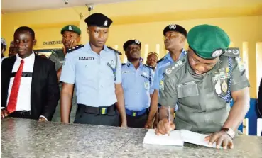  ??  ?? From right: Inspector General of Police, Ibrahim K. Idris, signs a visitors’ register during a visit to the Bompai Police Division, while the DPO of the Division, Daniel I. Amah, looks on