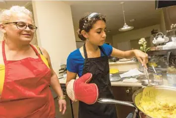  ?? MIAMI HERALD PHOTOS ?? Mother and daughter Naylin Sanchez, 48, and Adrienne Rosquete, 15, mix the pan of One Pot Coconut Curried Chicken during a cooking class hosted by FIU School of Hospitalit­y on Tuesday.