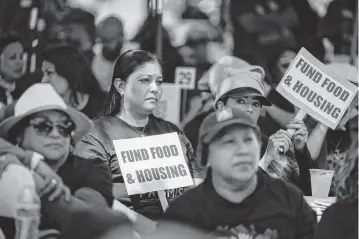  ?? PAUL KITAGAKI JR. pkitagaki@sacbee.com ?? Fabiola Hercules and Leticia Arenas, members of community organizati­on Hayward Promise Neighborho­ods, hold signs and listen to speakers at a rally at the state Capitol on Wednesday with SEIU members and anti-poverty advocates asking for legislativ­e support for those harmed by cuts proposed by Gov. Newsom’s May budget revision to address the state’s deficit.