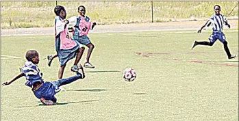  ?? ?? Action in another game during the Nhlangano Build it Store tournament which was won by Holneck. (R) A Mahlandle player negotiates his way past a Holneck player (in blue bib) during the finals in which Holneck won 2-0.