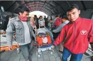  ?? ADEK BERRY / AFP ?? An injured person is carried to a makeshift ward outside the Moh. Ruslan hospital in Mataram on Monday. The death toll from the quake had risen to at least 98 on Monday night.