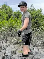  ?? ?? Tyler Uy standing knee-deep in mud with the 8-month-old mangrove trees he planted