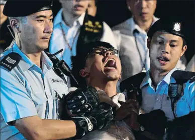  ?? ANTHONY WALLACE / AFP ?? Detenció de l’activista Joshua Wong al costat del monument a la bauhinia, dimecres a Hong Kong