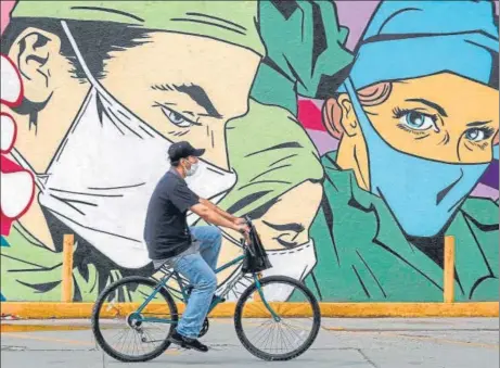  ??  ?? A man rides a bike past a mural by urban artists in Ciudad Juarez, Chihuahua state, Mexico.
AFP