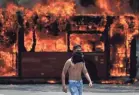  ?? FERNANDO LLANO/AP ?? An anti-government protester walks near a bus that was set on fire Tuesday.