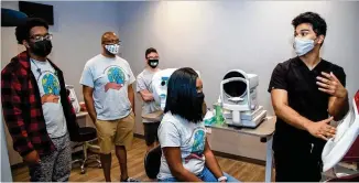  ?? PHOTOS BY PHIL SKINNER FOR THE AJC ?? Kevin Freeman (from left), Ryan Cox, Leonard Russell and Lashanta Cox listen to Thasin Wahid explain an eye test machine at First Class Eye Care in Duluth. Gwinnett Chatt Outreach takes high school students to businesses to show them different career opportunit­ies.