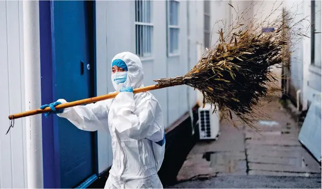  ??  ?? ↑
A worker wearing a hazmat suit as a preventive measure against the COVID-19 carries a broom in Huanggang Zhongxin Hospital in Huanggang, in China.
Agence France-presse