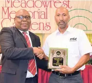  ??  ?? Christophe­r Lyew of Lee Mason’s Funeral Home receiving a trophy from Charles Simms, minister of the Funeral Services Committee, for Most Business.