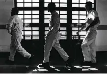  ?? Bob Owen / Staff photograph­er ?? Inmates in the McConnell Prison in Beeville walk by barred windows as they go to change their bedsheets.