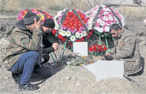  ?? REUTERS ?? Men mourn at the grave of a fallen soldier, who was killed during the military conflict over the breakaway region of Nagorno-Karabakh, in Stepanaker­t.