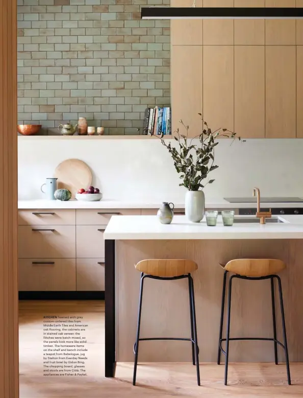  ??  ?? KITCHEN Teamed with grey custom-ordered tiles from Middle Earth Tiles and American oak flooring, the cabinets are in stained oak veneer; the flitches were batch-mixed, so the panels look more like solid timber. The homeware items on the shelf and bench include a teapot from Babelogue, jug by Stelton from Everday Needs and fruit bowl by Gidon Bing. The chopping board, glasses and stools are from Città. The appliances are Fisher &amp; Paykel.