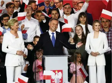  ??  ?? Polens Präsident Andrzej Duda, eingerahmt von seiner Frau Agata und Tochter Kinga (beide in Weiß), lässt sich nach dem Wahlsieg von seinen Unterstütz­ern feiern.
FOTO: GETTY