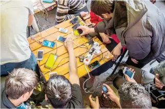  ??  ?? Migrants charge their mobile phones in a restaurant near the central bus station in Belgrade earlier this month. (AFP)