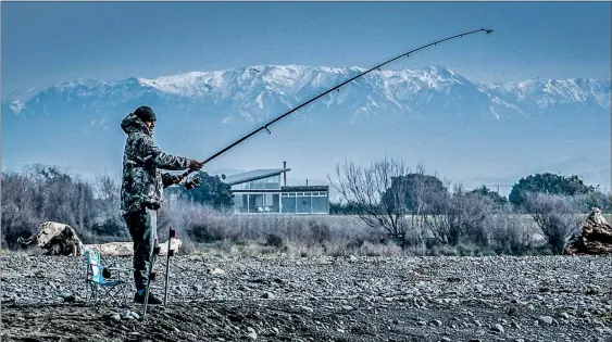  ?? PHOTO / PAUL TAYLOR ?? A fisherman wraps up warm at the Tukituki River mouth in Haumoana, with the snow-capped Kaweka Range on the horizon.