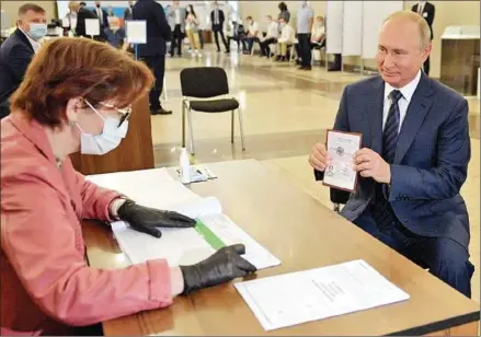  ?? SPUTNIK/AFP ?? State television showed Putin voting on Wednesday at his usual polling station at the Russian Academy of Sciences, where he was handed a ballot by an electoral worker wearing a surgical mask and gloves.