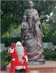  ?? — PTI ?? A man, dressed as Santa Claus, poses in front of Gandhi Smriti in New Delhi on Monday.