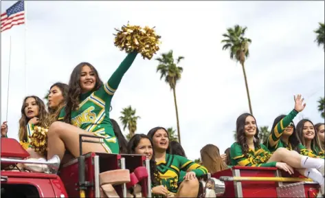  ?? VINCENT OSUNA PHOTO ?? Tanya Velarde (left) and the Holtville High School cheer team wave to the crowd while riding on top of a Holtville Fire Department fire truck in the 71st annual Holtville Carrot Festival parade on Saturday morning in Holtville.