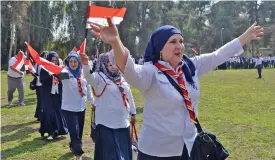  ?? (AFP) ?? This file photo shows Iraqi women Scout leaders walking with national flags during a training at the ‘Al-Hadbaa’ scout camp in Mosul on February 25