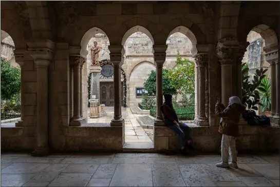  ?? PHOTOS BY SAMAR HAZBOUN — THE NEW YORK TIMES ?? Palestinia­n girls in the main courtyard at the Church of the Nativity in the West Bank city of Bethlehem on Dec. 13. The war in Gaza has prompted the city, traditiona­lly seen as the birthplace of Jesus, to tone down its Christmas celebratio­ns.