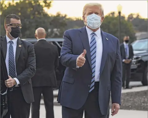  ?? Saul Loeb / Getty Images ?? President Donald Trump gestures after walking out of Walter Reed Medical Center in Bethesda, Maryland before heading to Marine One on Monday to return to the White House after being discharged.