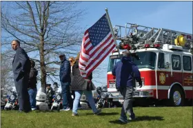  ?? RACHEL RAVINA - MEDIANEWS GROUP ?? A man walks by carrying an American flag Saturday afternoon during a funeral service for Branden T. Sisca, 29, at Perkiomen Valley High School, in Collegevil­le.