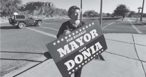  ?? Photos by Rick Bowmer, The Associated Press ?? Donia Jessop holds her mayoral campaign sign last month outside her store in Colorado City, Ariz., which sits just across the border from its sister city of Hildale, Utah. Campaign signs are unusual in a town where elections have long been quietly...