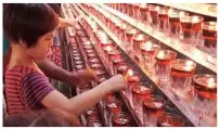  ??  ?? Max, Melinda’s son, lighting up an oil lamp for family at the temple.