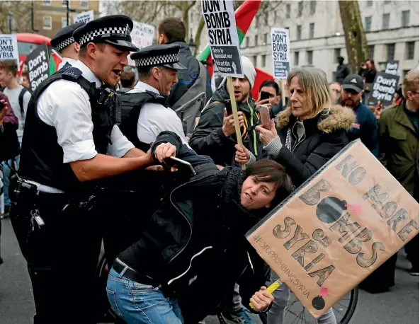  ??  ?? A policeman tussles with a protester near Downing Street in London during a demonstrat­ion yesterday organised by the Stop the War Coalition against military interventi­on or bombing by Western allies in Syria. The US, Britain and France have launched air strikes in retaliatio­n for Syria’s use of chemical weapons against civilians.