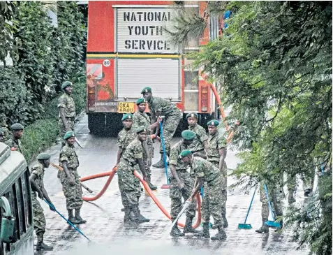  ??  ?? Kenya’s National Youth Service personnel clean the road to a hotel complex in Nairobi, where an attack by al-Shabaab left 21 people dead, including a British charity chief