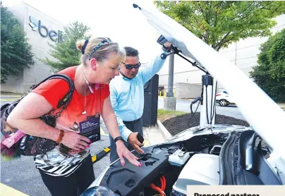  ?? STAFF PHOTO BY ANGELA LEWIS FOSTER ?? Julian Espiritu, right, shows Patricia Sager features of a car at the celebratio­n of Chattanoog­a’s electric vehicle car share “First Plug-In” Tuesday at Hamilton Place mall.