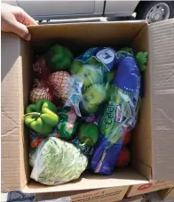  ?? Associated Press ?? ■ A volunteer shows a box filled with produce to be given away at a drive-up produce giveaway organized by a Des Moines food pantry in Des Moines, Iowa.