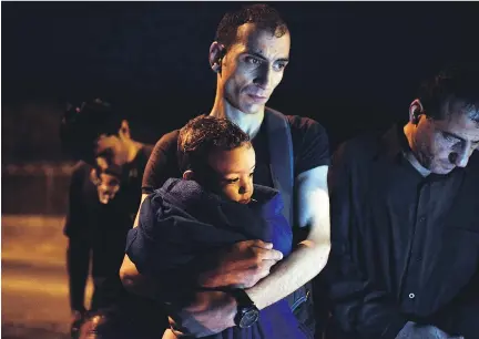  ?? LOUISA GOULIAMAKI/AFP/GETTY IMAGES FILES ?? A migrant from Syria holds his baby as they arrive on the island of Lesbos in June. By last Friday, more than 68,000 migrants from Africa, the Middle East and South Asia had reached Greece by sea this year.