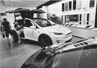  ?? Richard Vogel / Associated Press ?? Customers check out the Tesla X at the Tesla showroom in Santa Monica, Calif. The stock gained after Elon Musk tweeted he was mulling taking the company private, but the gains have vanished.