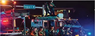  ??  ?? St Louis County Police officers, outfitted in tactical equipment, monitor the situation in Ferguson, Missouri on August 10, 2015. — AFP