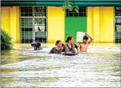  ?? FERDINANDH CABRERA/AFP ?? Residents evacuate in the Philippine­s on Saturday after Tropical Storm Tembin dumped torrential rains there.