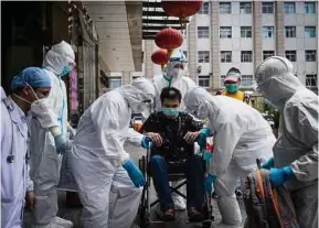  ?? (Foto AFP) ?? Kakitangan barisan hadapan bersama pesakit terakhir yang sembuh selepas dirawat di sebuah hospital di Wuhan.
